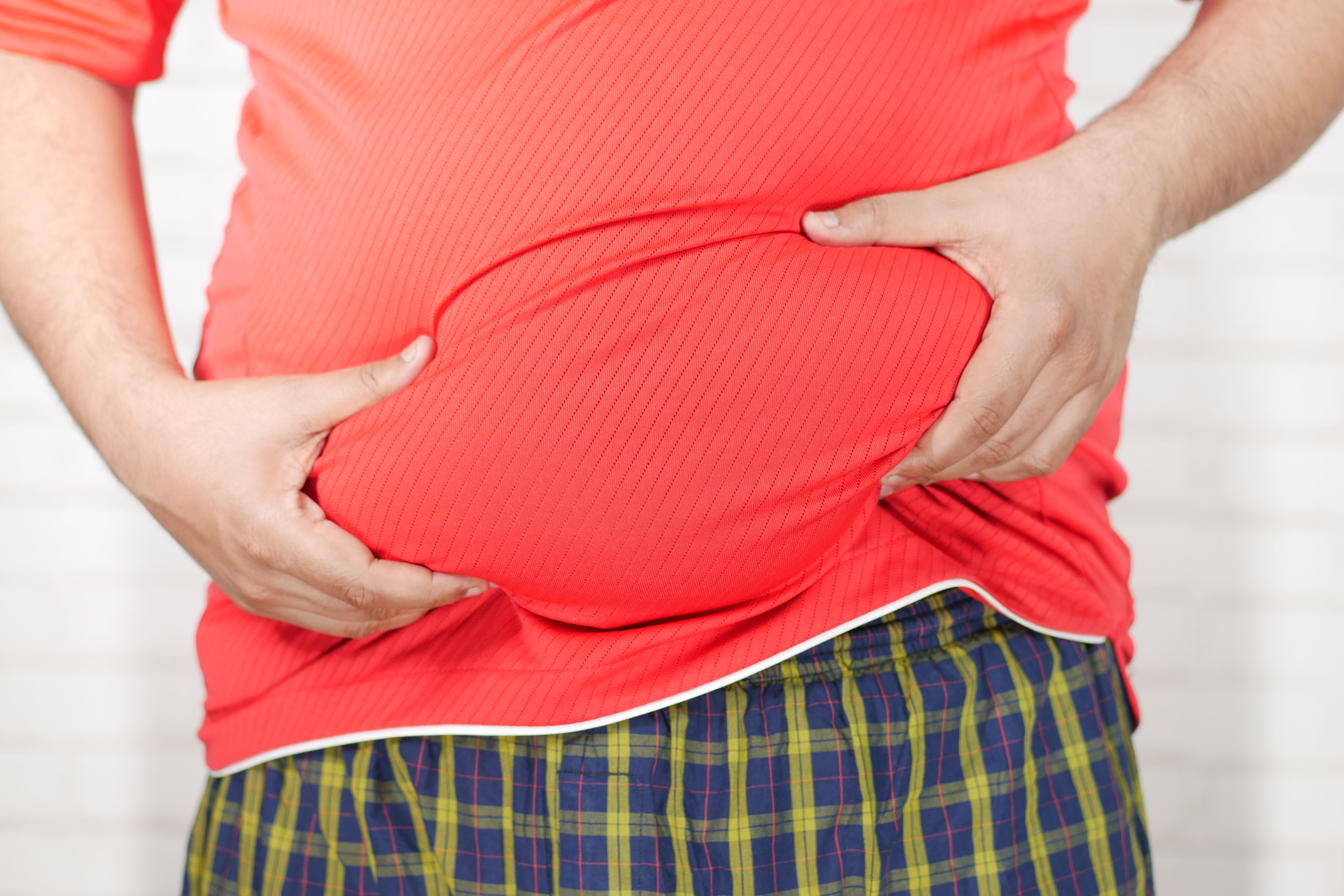 person-holding-their-belly-fat-in-a-red-tshirt 